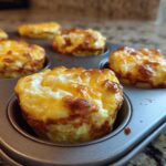 Close-up of freshly baked, golden-brown Egg Muffin Cups still resting in a metal muffin tin.