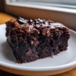 Close-up of a moist, fudgy square of black bean brownies topped with melted chocolate chips.
