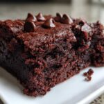 A close-up of a rich, dark, fudgy sweet potato brownies slice topped with chocolate chips.