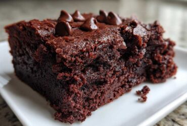 A close-up of a rich, dark, fudgy sweet potato brownies slice topped with chocolate chips.