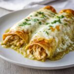 Close-up of two delicious green chile chicken enchiladas covered in melted white cheese and cilantro.