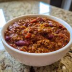 Close-up of a rich, thick bowl of crockpot chili featuring ground beef and kidney beans.