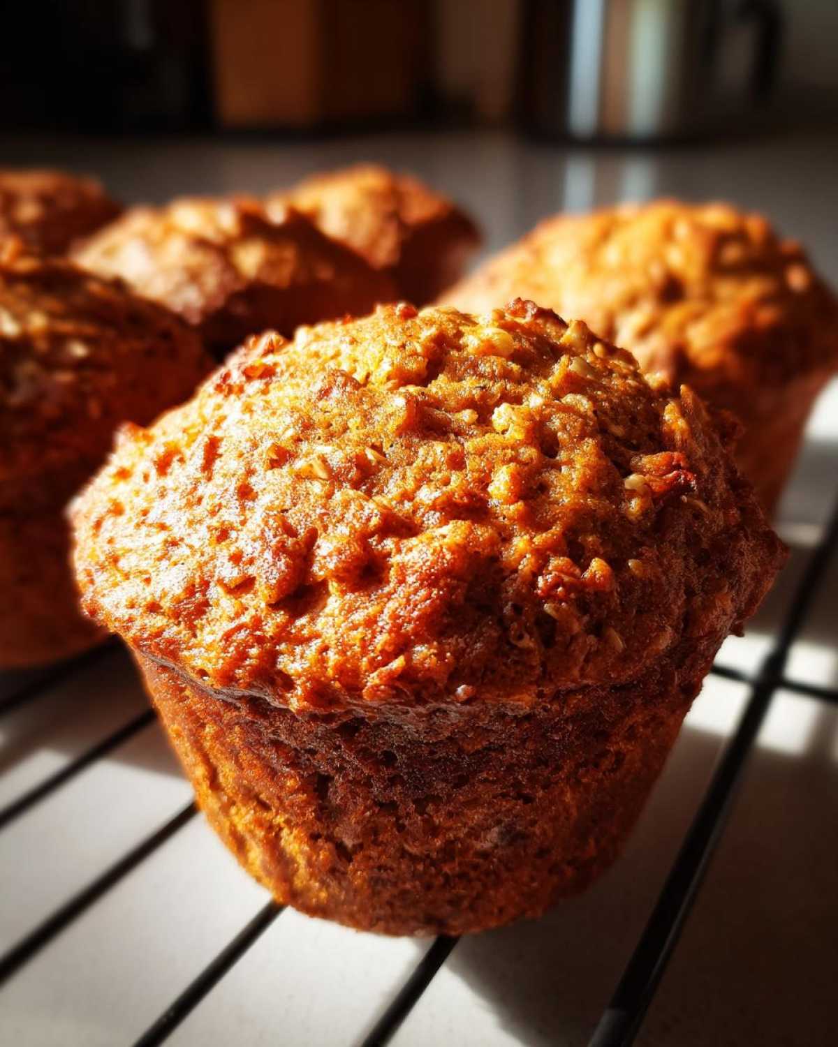 Close-up of a perfectly baked honey bran muffin with a textured, golden-brown top, cooling on a wire rack.