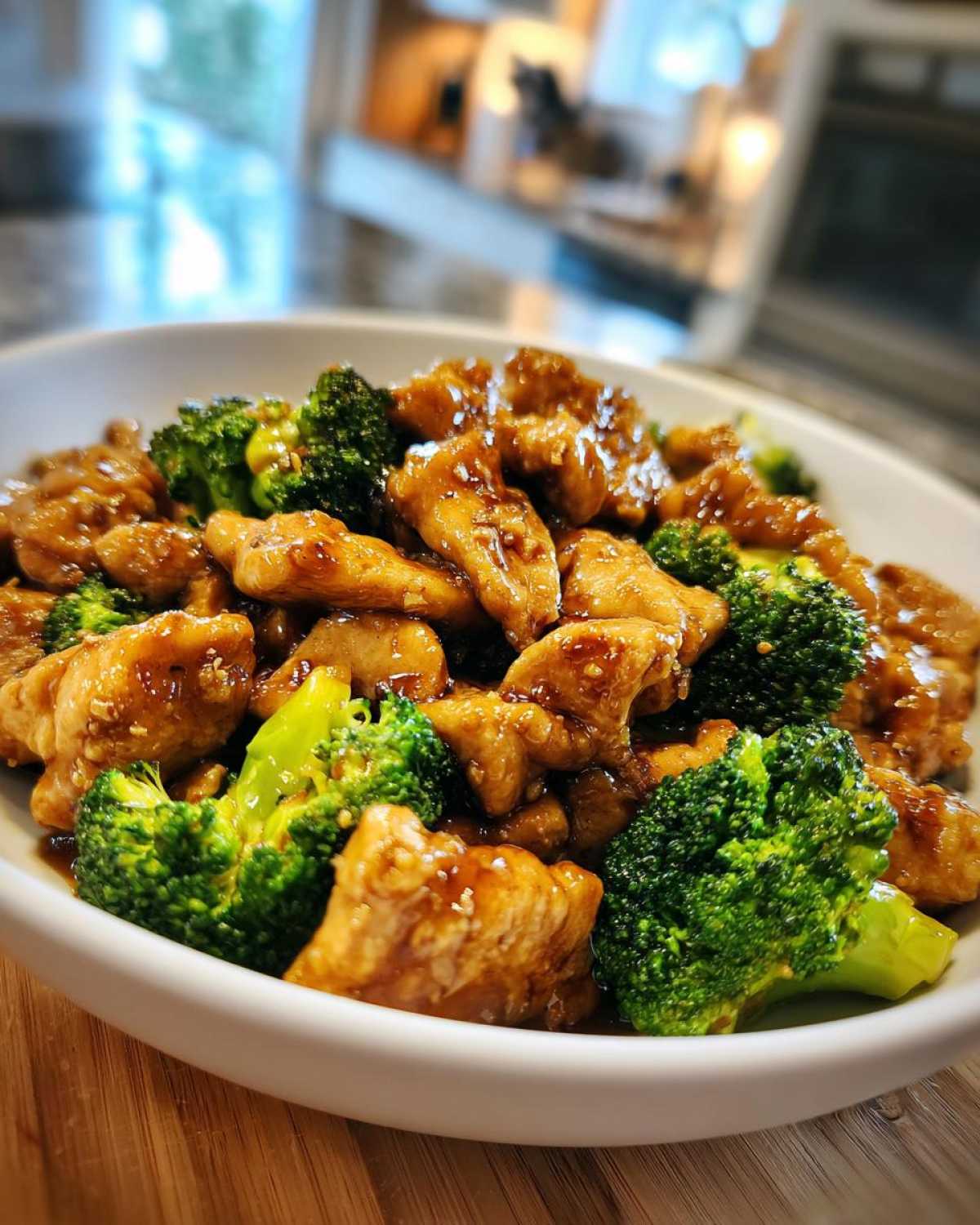 Close-up of glossy honey garlic chicken and broccoli pieces served in a white bowl.