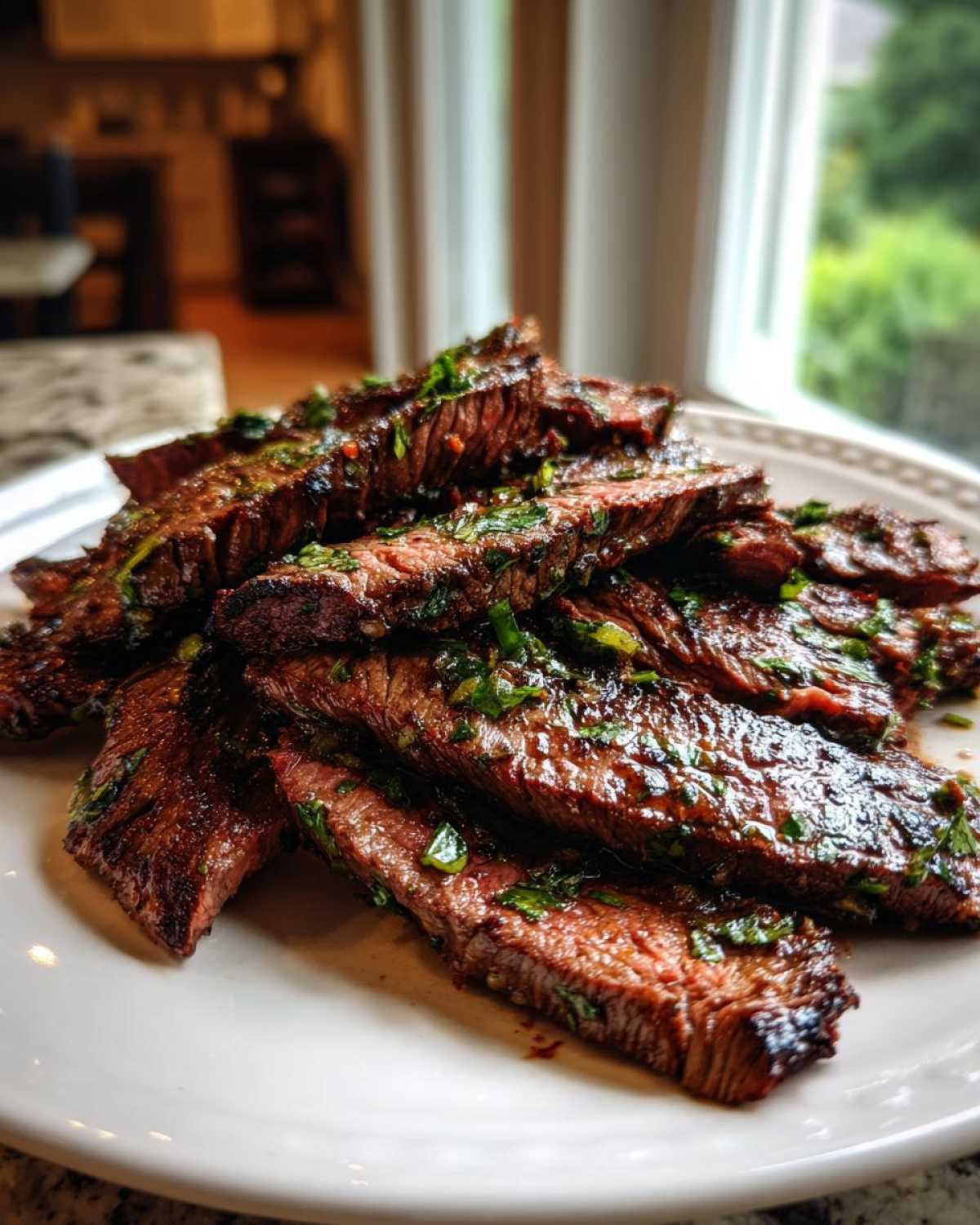 Pile of perfectly grilled and sliced steak coated in herbs, showcasing the results of the carne asada marinade.