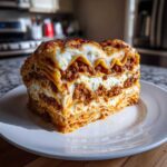 A thick, tall slice of Lasagna with Cottage Cheese, showing layers of pasta, rich meat sauce, and white cheese filling.