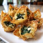 Close-up of crispy, golden-brown Mediterranean Spinach and Feta Cheese Crisps served on a white plate.