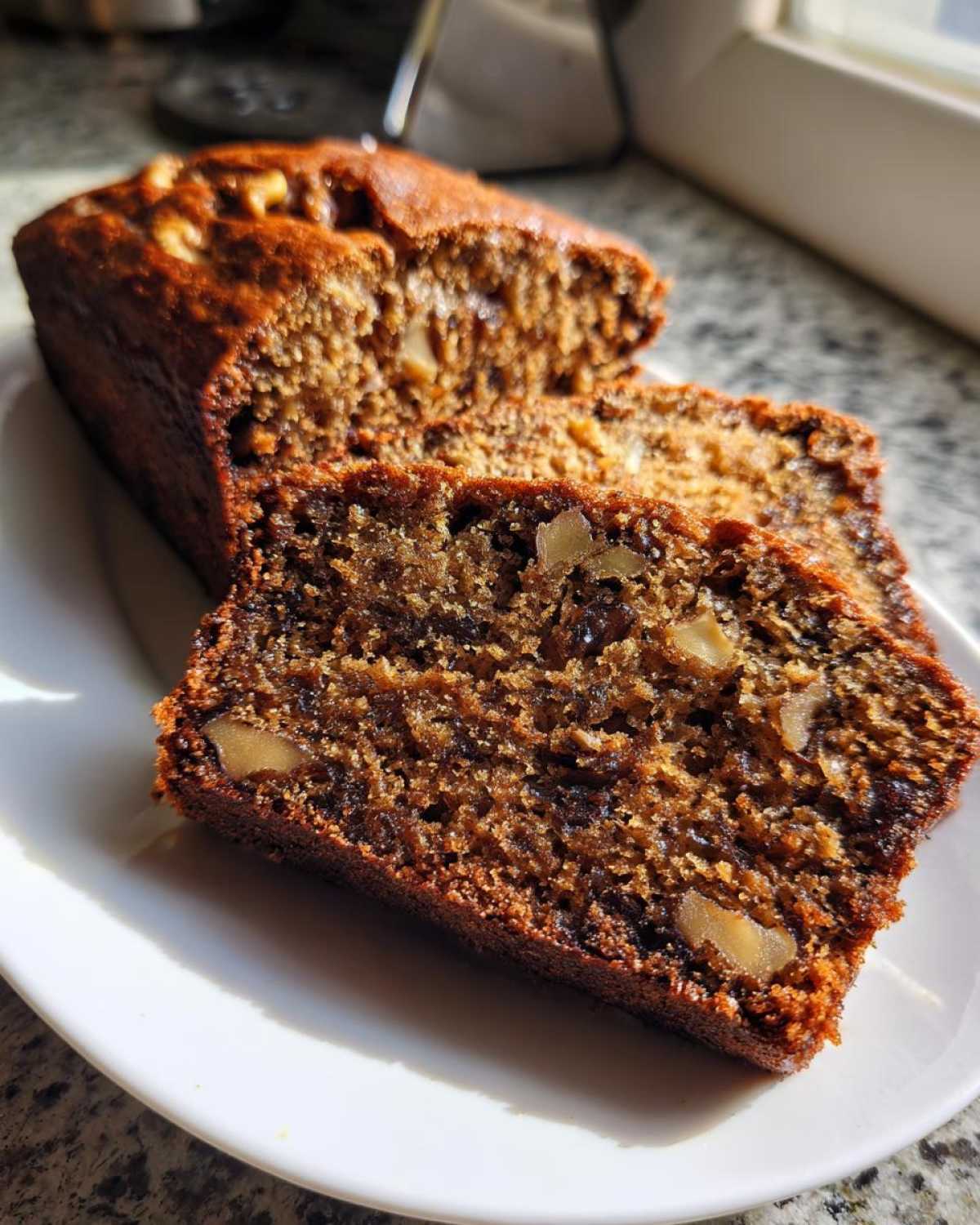 Close-up of moist date nut bread slices showing dark texture, dates, and visible walnuts.