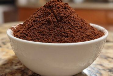 Close-up of a heaping mound of rich brown hot cocoa mix filling a small white bowl.