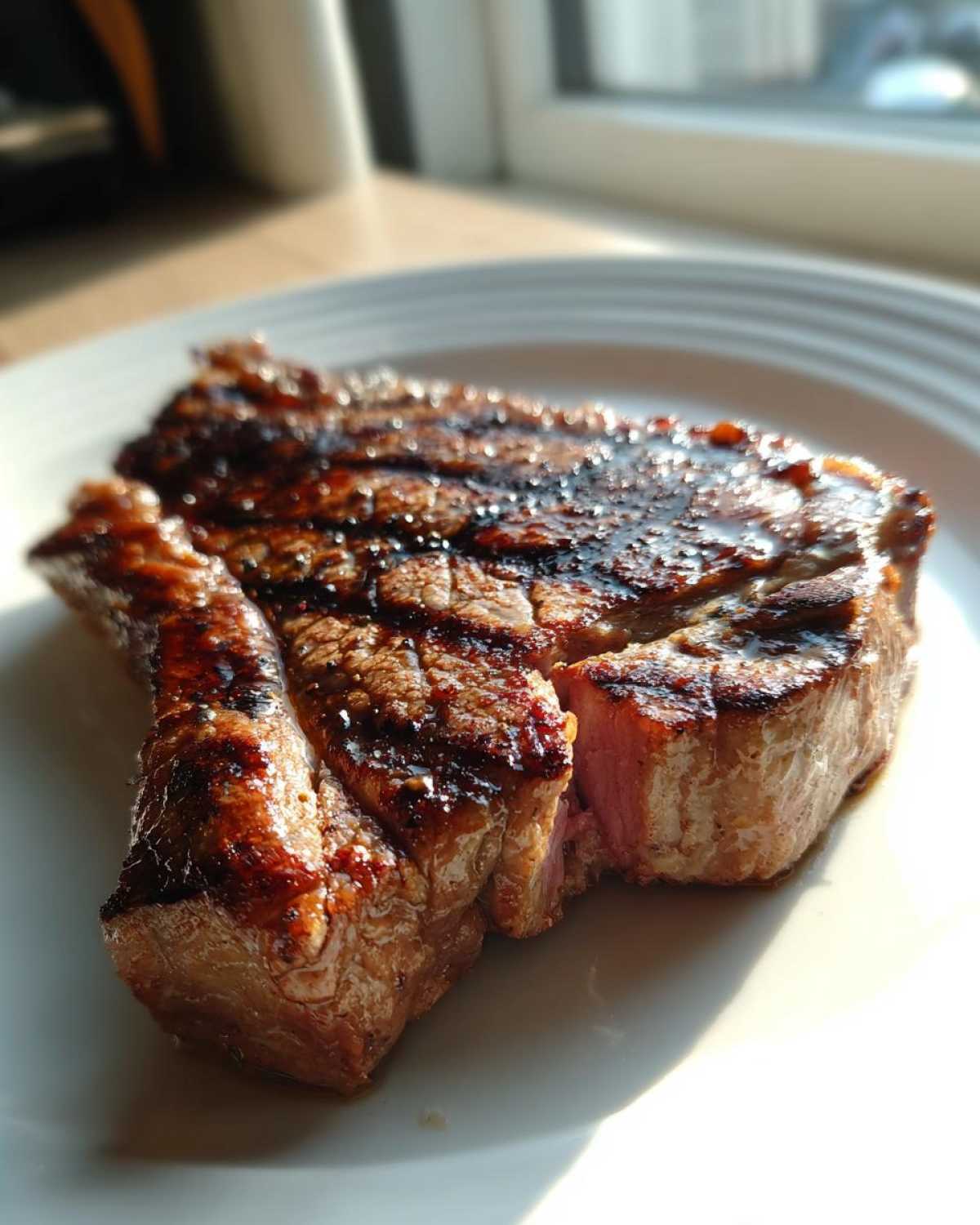 Close-up of a juicy, grilled pork steak recipe slice showing grill marks and a medium-rare center.