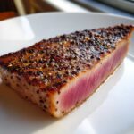 Close-up of a perfectly seared tuna steak, rare in the center, coated in a cracked pepper crust, ready after using the MARINADE FOR TUNA STEAK.