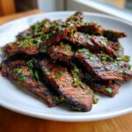 Close-up of grilled, sliced steak generously topped with a bright green herb sauce, showcasing the results of the carne asada marinade.