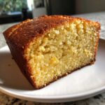 Close-up of a moist slice of golden sourdough cornbread with a dark, caramelized crust.