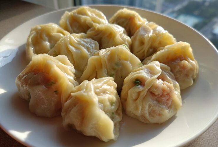 A plate of freshly steamed Traditional Chinese Dumplings with visible filling, highlighted by bright sunlight.