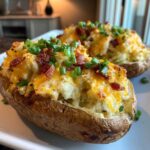 Close-up of a fluffy twice-baked potato loaded with melted cheddar cheese, bacon bits, and fresh green chives.