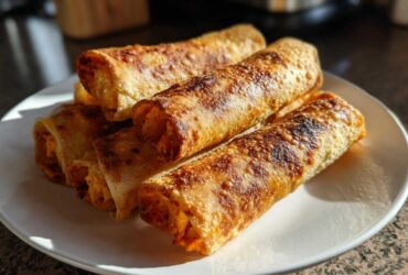 A stack of golden brown, crispy Air Fryer Buffalo Chicken Taquitos served on a white plate.