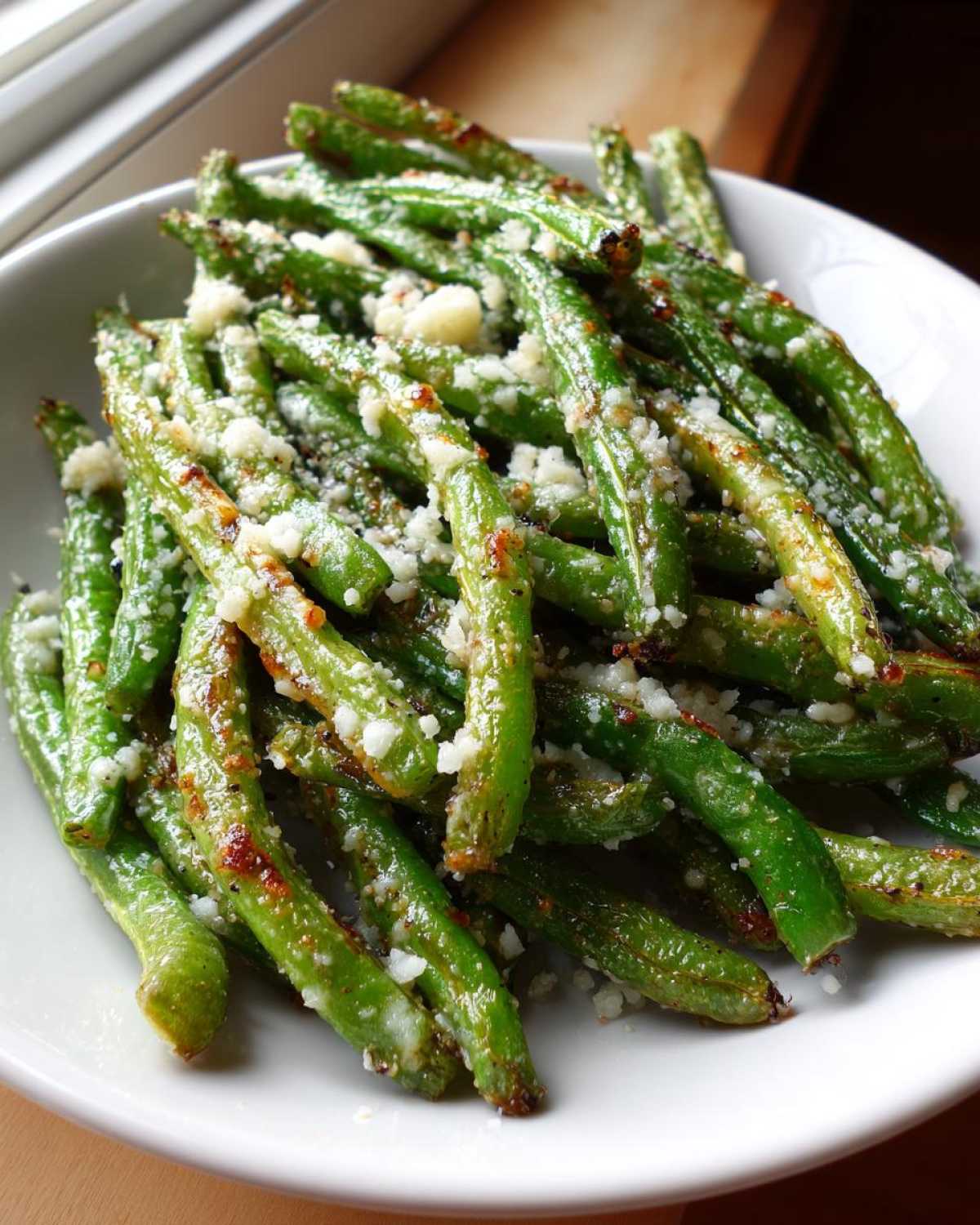 Close-up of vibrant green beans tossed with grated Parmesan cheese, ready to serve as Air Fryer Garlic Parmesan Green Beans.