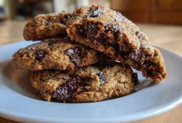 A stack of three Gluten-Free Irish Oat Cookies with dark chocolate chunks and a sugar topping on a white plate.