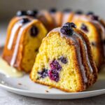 A close-up of a slice of moist Gluten-Free Lemon Blueberry Bundt Cake drizzled with lemon glaze.