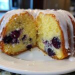 Cross section of a moist Gluten-Free Lemon Blueberry Bundt Cake showing blueberries inside and a lemon glaze on top.