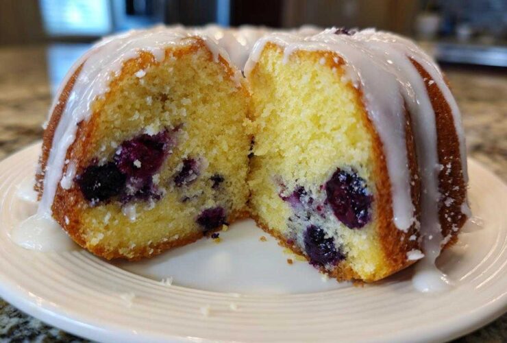 Cross section of a moist Gluten-Free Lemon Blueberry Bundt Cake showing blueberries inside and a lemon glaze on top.
