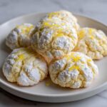 Close-up of several Gluten-Free Lemon Meltaway Cookies dusted with powdered sugar and drizzled with glaze.