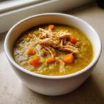 A white bowl filled with thick, green Instant Pot Split Pea Soup with Smoked Turkey and diced carrots.