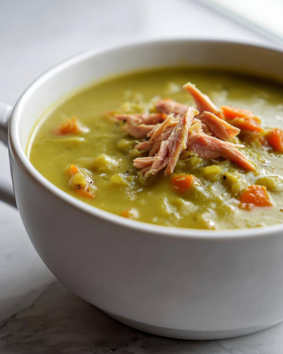 Close-up of creamy Instant Pot Split Pea Soup with Smoked Turkey and diced carrots.