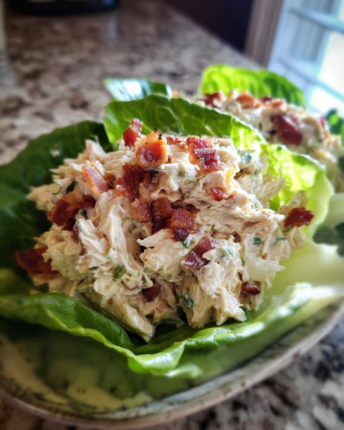 Close-up of Keto Bacon Ranch Chicken Salad served in crisp lettuce cups, topped with crumbled bacon.