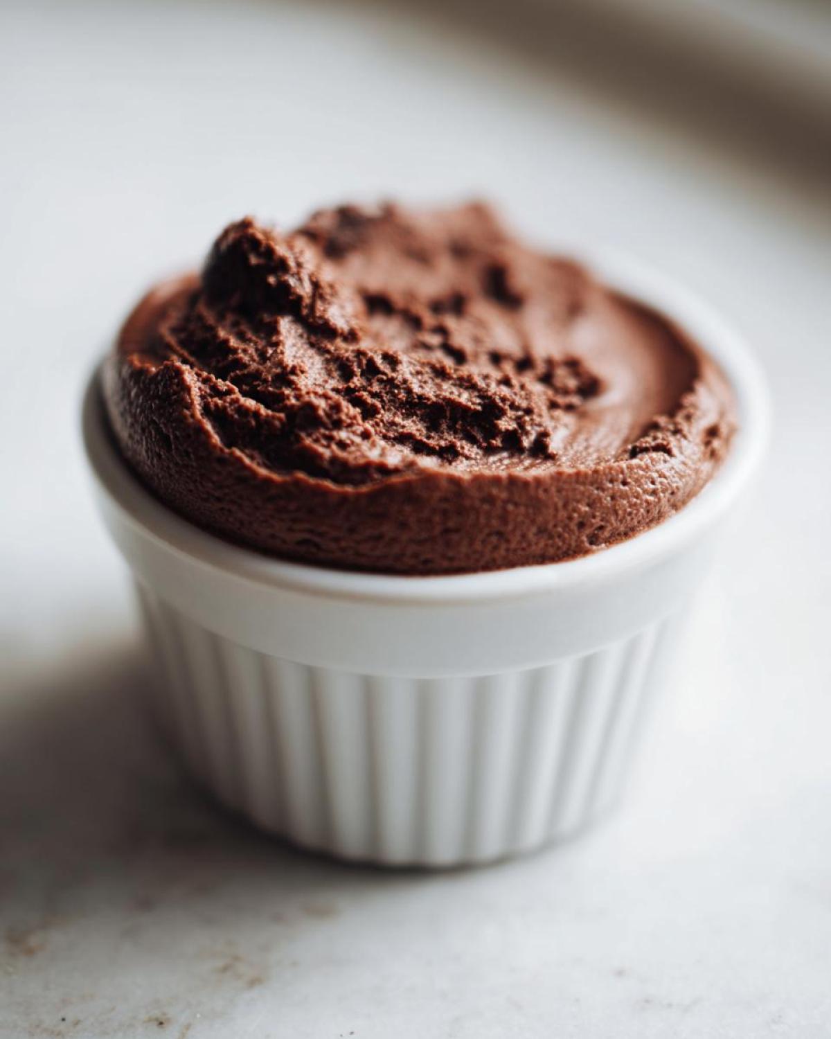 Close-up of rich, dark Keto Creamy Chocolate Cheesecake Mousse served in a white fluted ramekin.