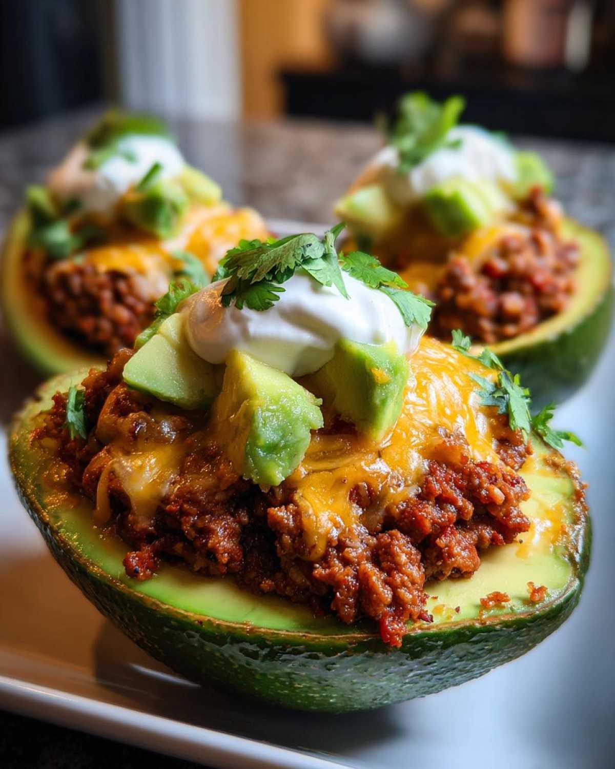 A close-up of a Keto Taco Stuffed Avocado filled with seasoned ground meat, melted cheese, and topped with sour cream and cilantro.