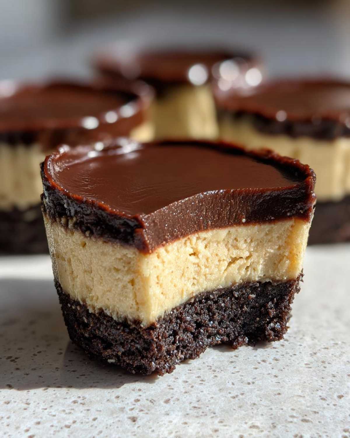 Close-up of a No-Bake Chocolate Peanut Butter Cheesecake Cup showing the dark crust, peanut butter filling, and chocolate ganache top.
