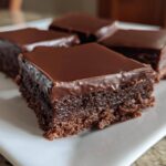 Four rich squares of No-Bake Espresso Chocolate Fudge Squares with a shiny chocolate glaze on a white plate.