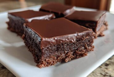Four rich squares of No-Bake Espresso Chocolate Fudge Squares with a shiny chocolate glaze on a white plate.
