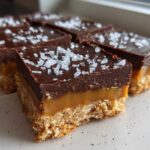 Close-up of several No-Bake Salted Caramel Pretzel Bars topped with flaky sea salt.