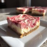 A single serving of No-Bake Strawberry Lemon Cheesecake Bars with a graham cracker crust and swirled topping.