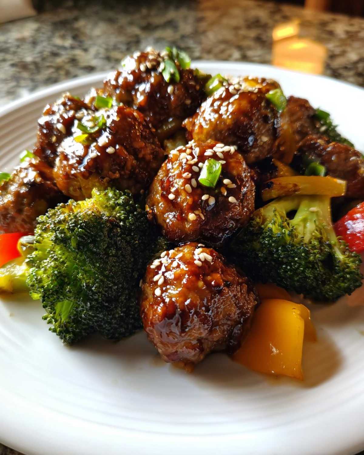 Close-up of glazed Sheet Pan Ginger Sesame Chicken Meatballs served with bright green broccoli florets.