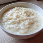 Close-up of a white bowl filled with creamy Vegan Creamy Coconut Rice Pudding.