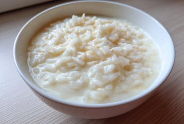 Close-up of a white bowl filled with creamy Vegan Creamy Coconut Rice Pudding.