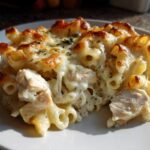 Close-up of a serving of Cheesy Chicken Alfredo Pasta Bake with mozzarella topping browned under the broiler.