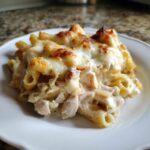 A close-up of a serving of Cheesy Chicken Alfredo Pasta Bake with Mozzarella, featuring baked, bubbly cheese.