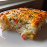 A close-up of a square serving of Cheesy Chicken and Rice Casserole Easy Bake with a golden, melted cheese top.