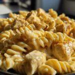 Close-up of rotini pasta coated in a rich, creamy sauce with chunks of seasoned chicken, highlighting the Cheesy Chicken Pasta with Creamy Sauce.