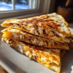 Three stacked slices of a golden-brown Cheesy Chicken Quesadilla with Creamy Filling, showing shredded chicken and melted cheese.