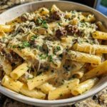 A close-up of a bowl filled with Cheesy Ground Beef Pasta with Garlic Cream Sauce, topped with grated cheese and parsley.