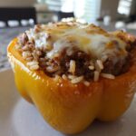 A close-up of one baked yellow bell pepper filled with Cheesy Ground Beef Stuffed Peppers with Rice mixture.