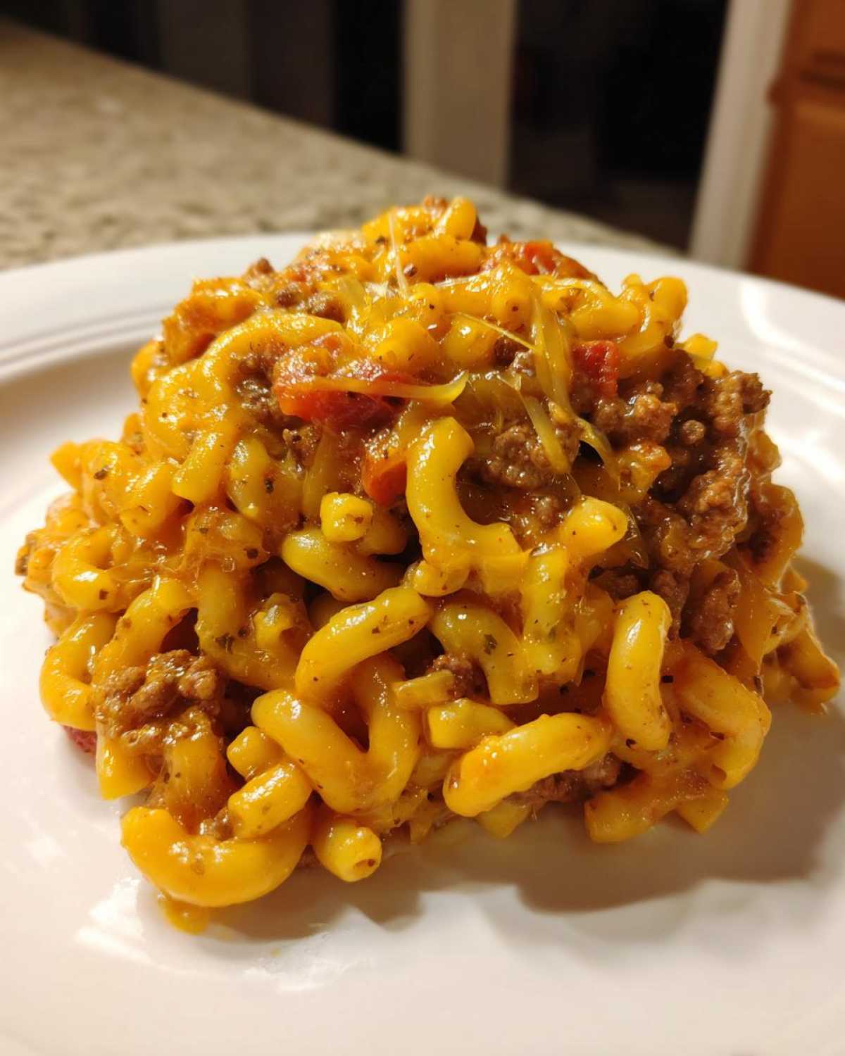A close-up serving of Cheesy Taco Pasta One Pot Dinner Idea featuring elbow macaroni, ground beef, and melted cheddar cheese.