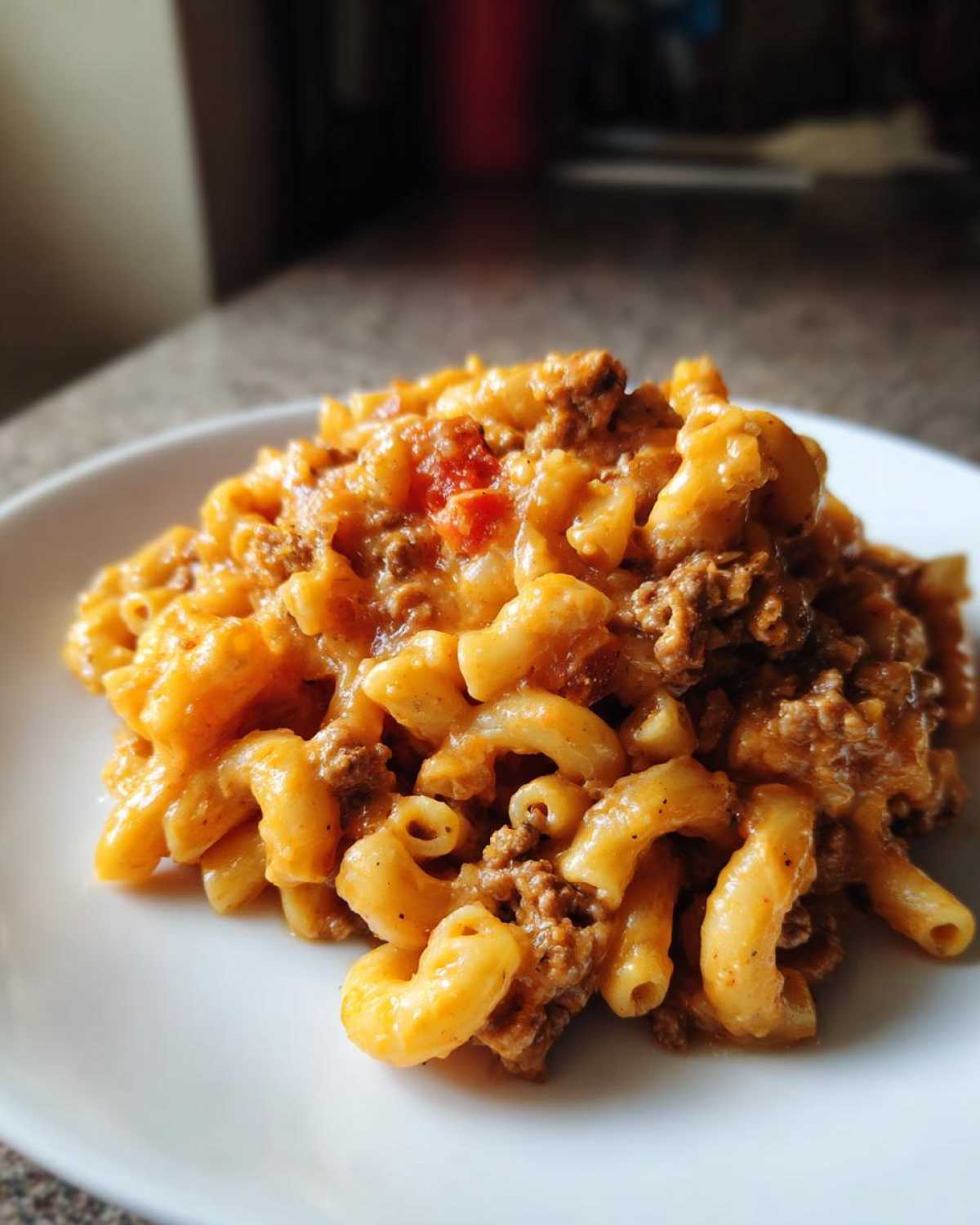 A serving of Cheesy Taco Pasta One Pot Dinner Idea featuring elbow macaroni coated in a creamy, orange cheese sauce with ground beef.