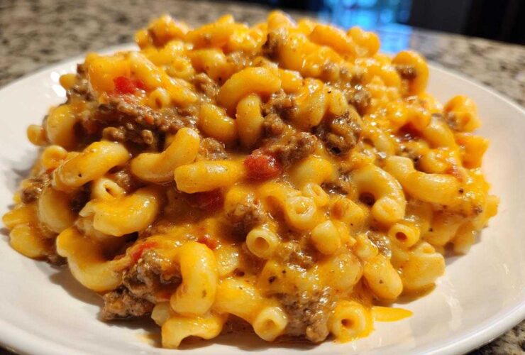 A close-up serving of Cheesy Taco Pasta One Pot Dinner Idea, featuring elbow macaroni mixed with ground beef and melted orange cheese sauce.