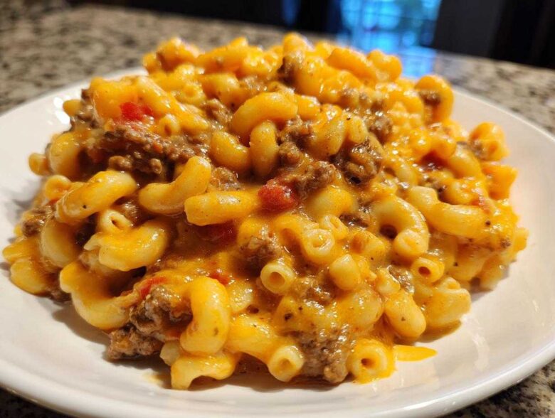 A close-up serving of Cheesy Taco Pasta One Pot Dinner Idea, featuring elbow macaroni mixed with ground beef and melted orange cheese sauce.